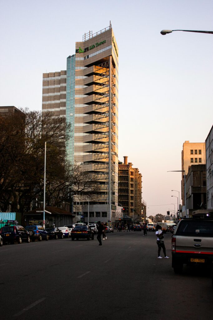 High-rise building in downtown Harare, Zimbabwe with cars on the street at dusk.